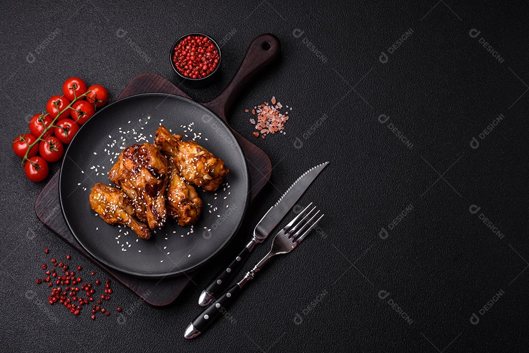 Deliciosas asas grelhadas crocantes com molho teriyaki com sal, especiarias e ervas sobre um fundo escuro de concreto