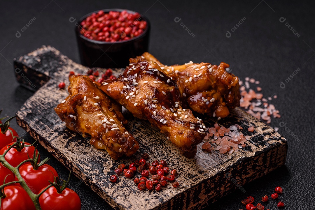 Deliciosas asas grelhadas crocantes com molho teriyaki com sal, especiarias e ervas sobre um fundo escuro de concreto