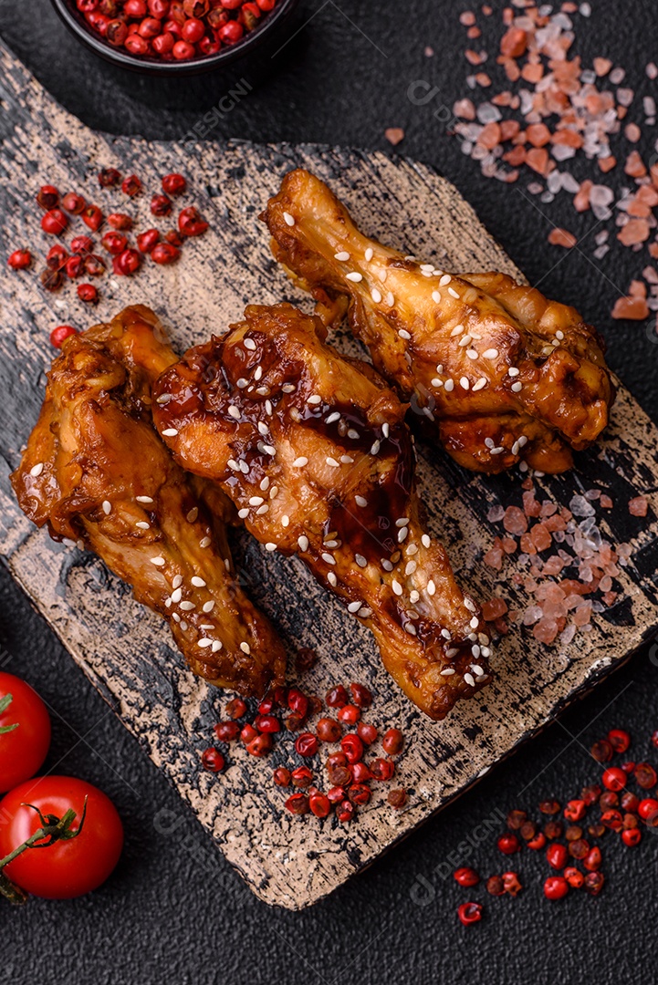 Deliciosas asas grelhadas crocantes com molho teriyaki com sal, especiarias e ervas sobre um fundo escuro de concreto