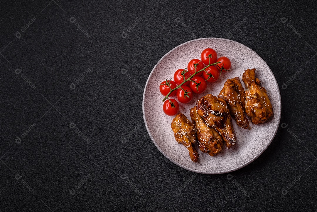 Deliciosas asas grelhadas crocantes com molho teriyaki com sal, especiarias e ervas sobre um fundo escuro de concreto