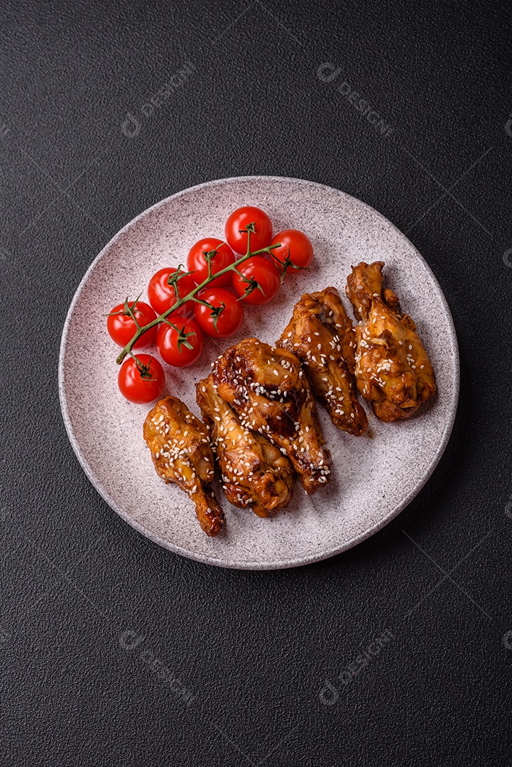 Deliciosas asas grelhadas crocantes com molho teriyaki com sal, especiarias e ervas sobre um fundo escuro de concreto