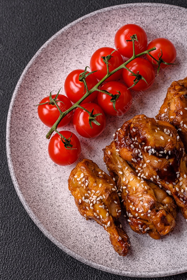 Deliciosas asas grelhadas crocantes com molho teriyaki com sal, especiarias e ervas sobre um fundo escuro de concreto