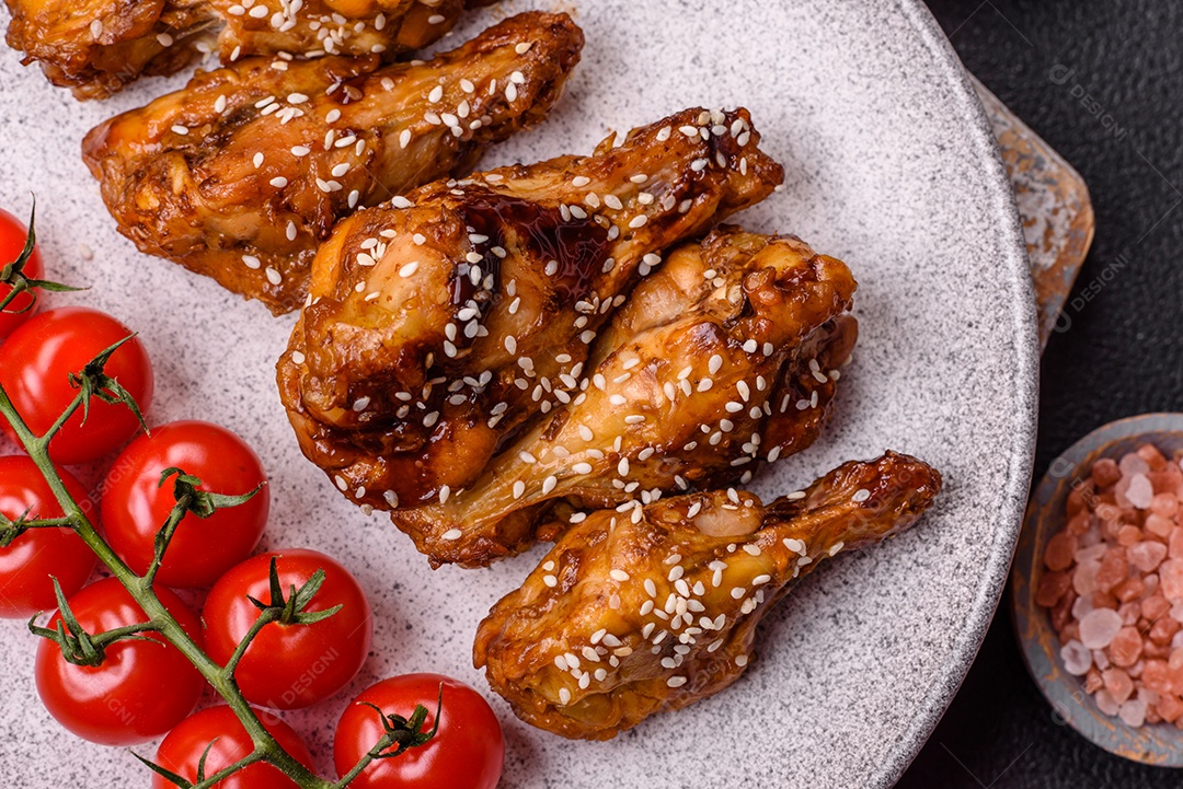 Deliciosas asas grelhadas crocantes com molho teriyaki com sal, especiarias e ervas sobre um fundo escuro de concreto