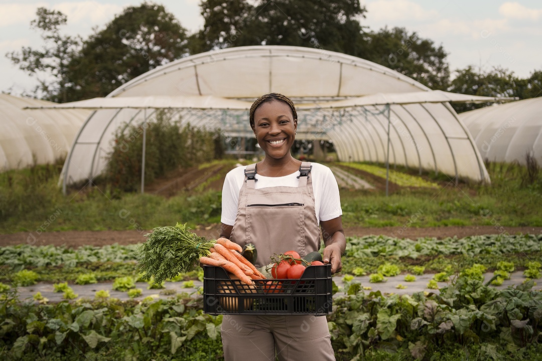 Mulher agricultora segurando caixa com sua colheita de verduras e vegetais