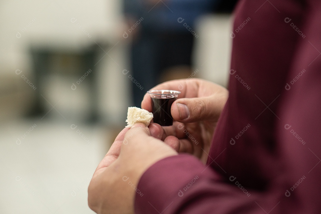 Mãos de uma pessoa com vinho e pão para ceiar