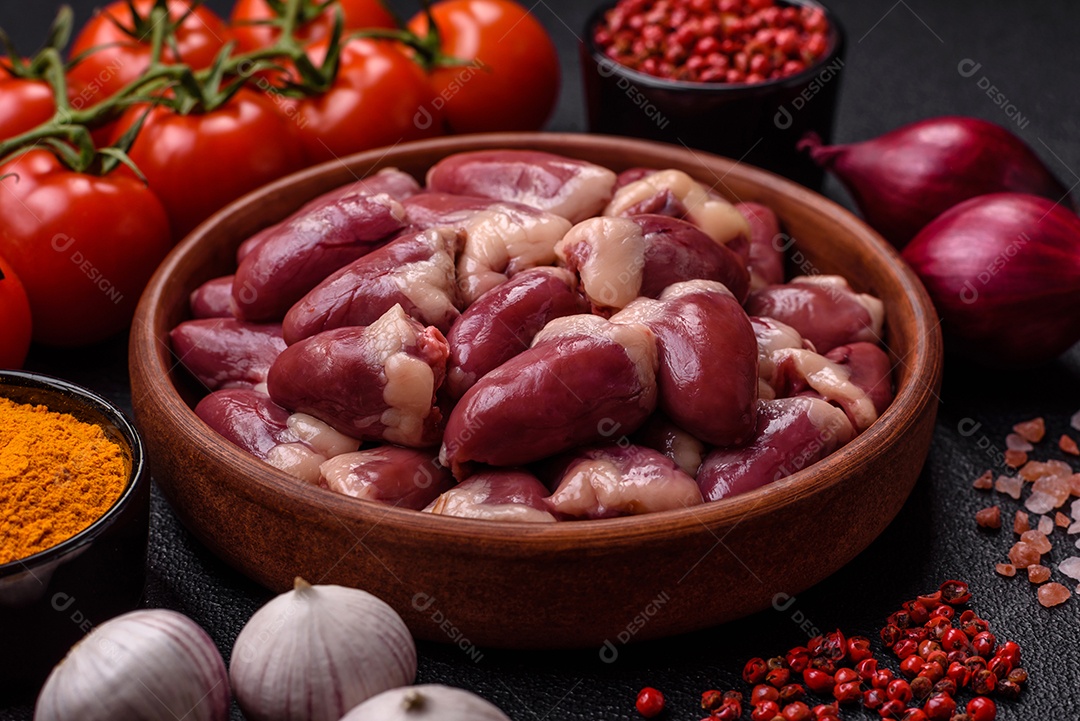 Corações de frango cru com sal, especiarias e ervas sobre um fundo escuro de concreto