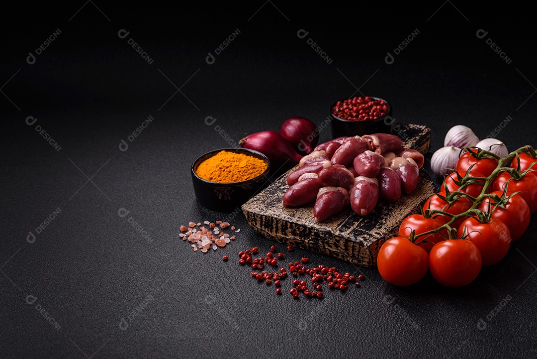 Corações de frango cru com sal, especiarias e ervas sobre um fundo escuro de concreto