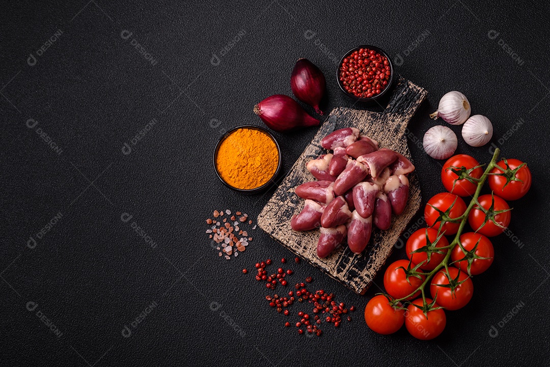 Corações de frango cru com sal, especiarias e ervas sobre um fundo escuro de concreto