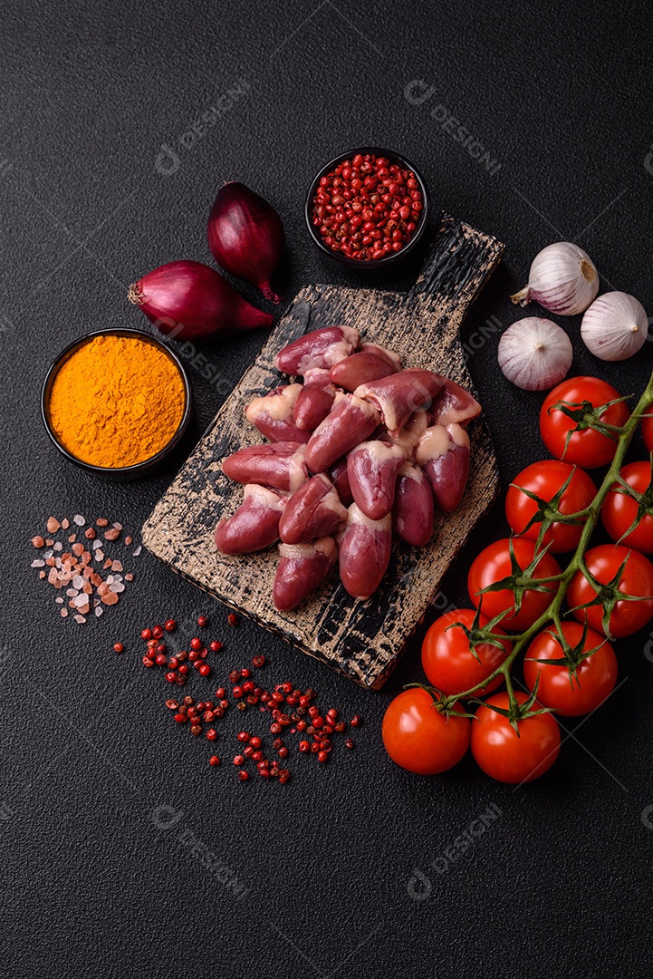 Corações de frango cru com sal, especiarias e ervas sobre um fundo escuro de concreto