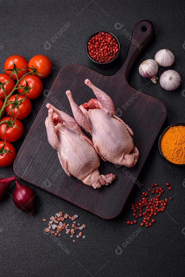 Codornizes cruas inteiras com sal, especiarias e ervas sobre um fundo escuro de concreto preparado para assar