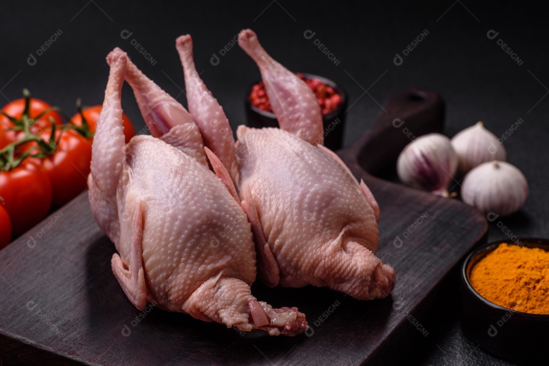 Codornizes cruas inteiras com sal, especiarias e ervas sobre um fundo escuro de concreto preparado para assar