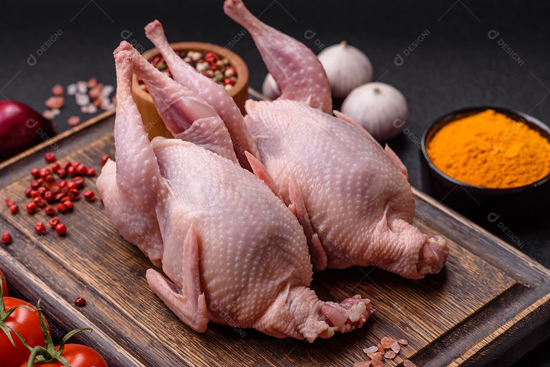 Codornizes cruas inteiras com sal, especiarias e ervas sobre um fundo escuro de concreto preparado para assar