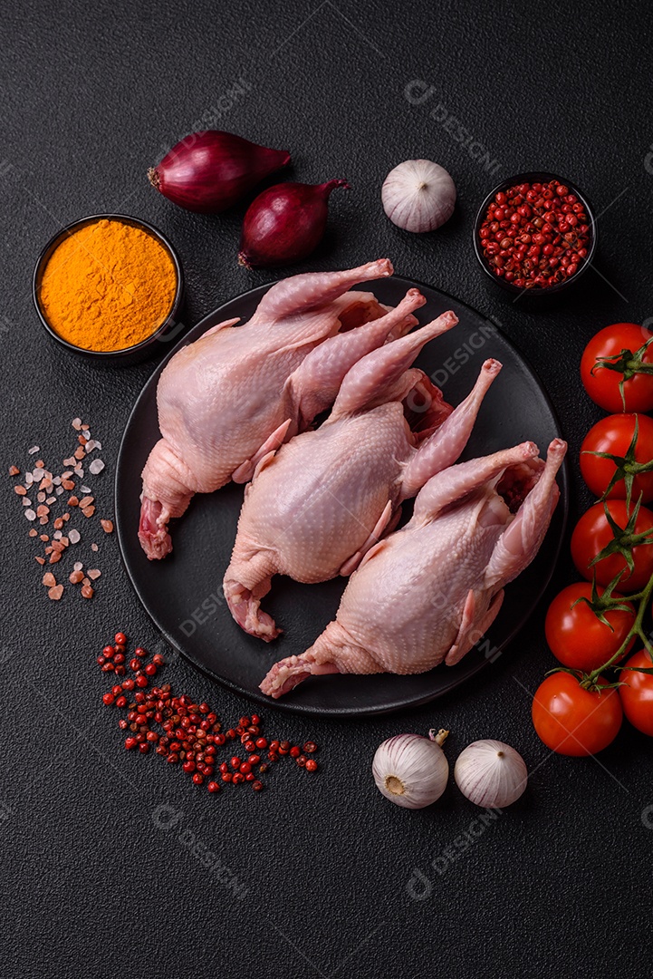 Codornizes cruas inteiras com sal, especiarias e ervas sobre um fundo escuro de concreto preparado para assar