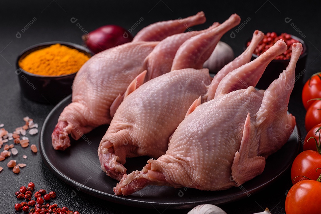 Codornizes cruas inteiras com sal, especiarias e ervas sobre um fundo escuro de concreto preparado para assa