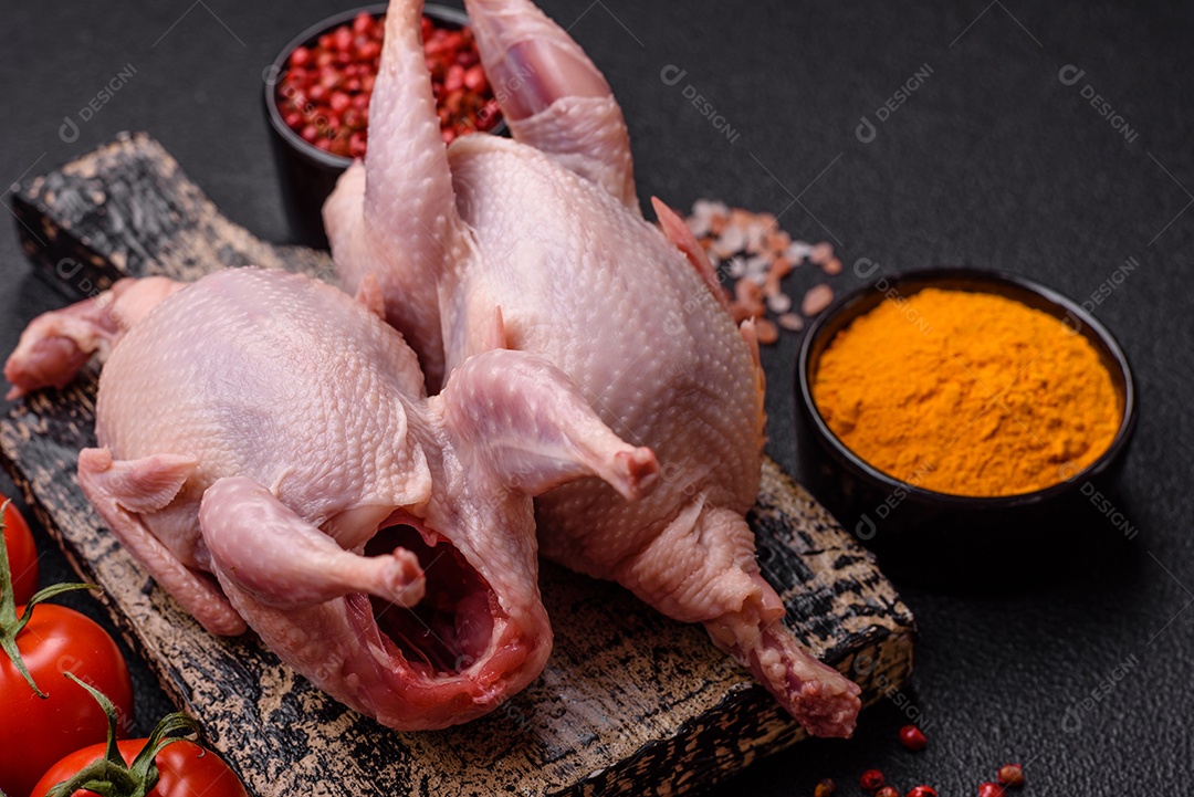 Pernas de frango cru com sal, especiarias e ervas sobre um fundo escuro de concreto preparado para assar