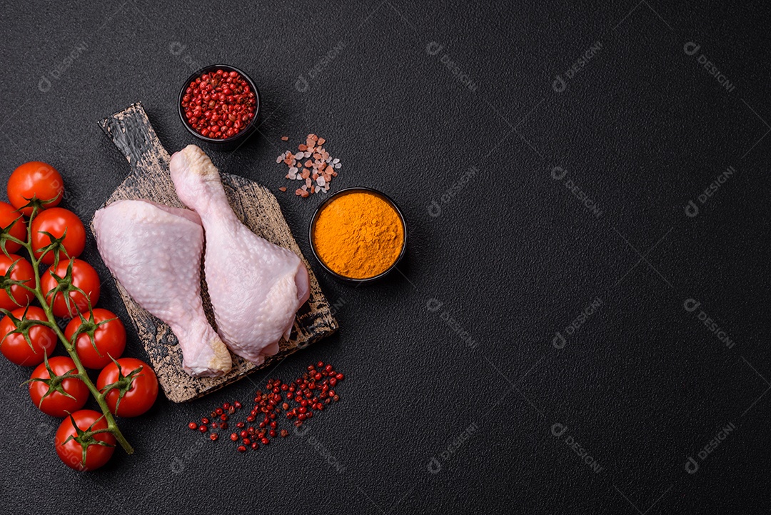 Pernas de frango cru com sal, especiarias e ervas sobre um fundo escuro de concreto preparado para assar