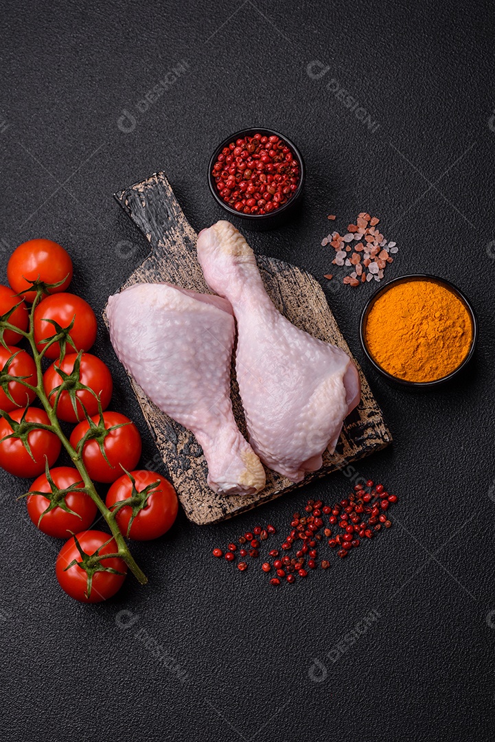 Pernas de frango cru com sal, especiarias e ervas sobre um fundo escuro de concreto preparado para assar