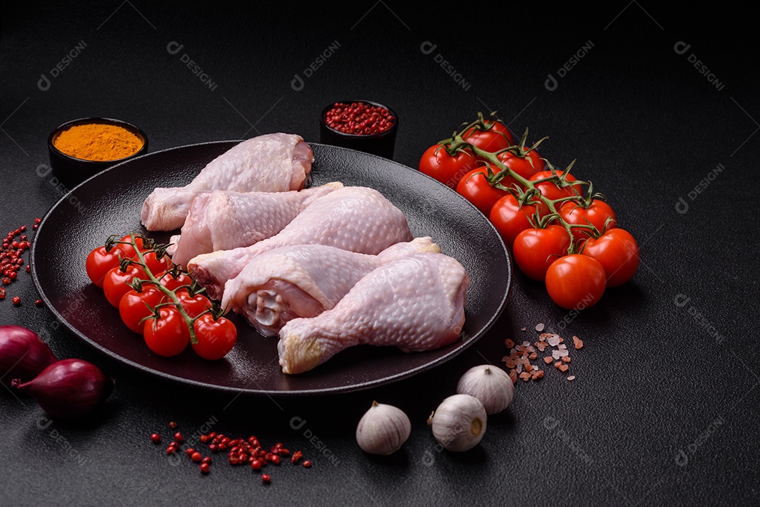 Pernas de frango cru com sal, especiarias e ervas sobre um fundo escuro de concreto preparado para assar