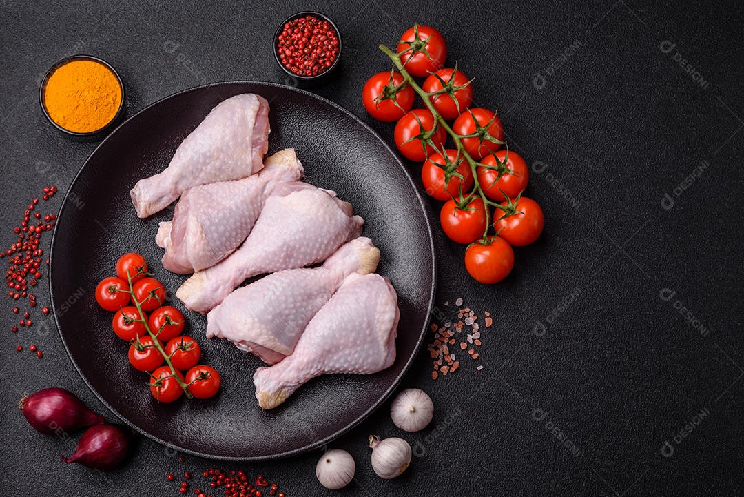 Pernas de frango cru com sal, especiarias e ervas sobre um fundo escuro de concreto preparado para assar