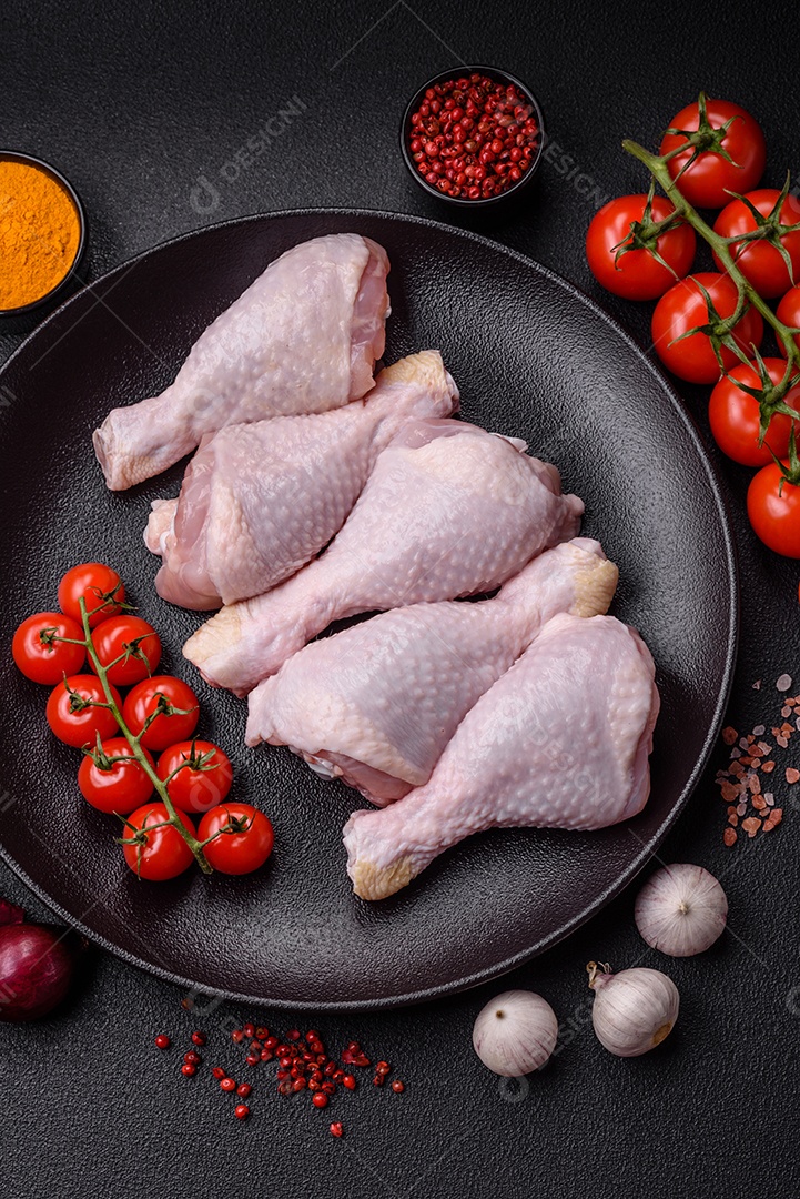 Pernas de frango cru com sal, especiarias e ervas sobre um fundo escuro de concreto preparado para assar