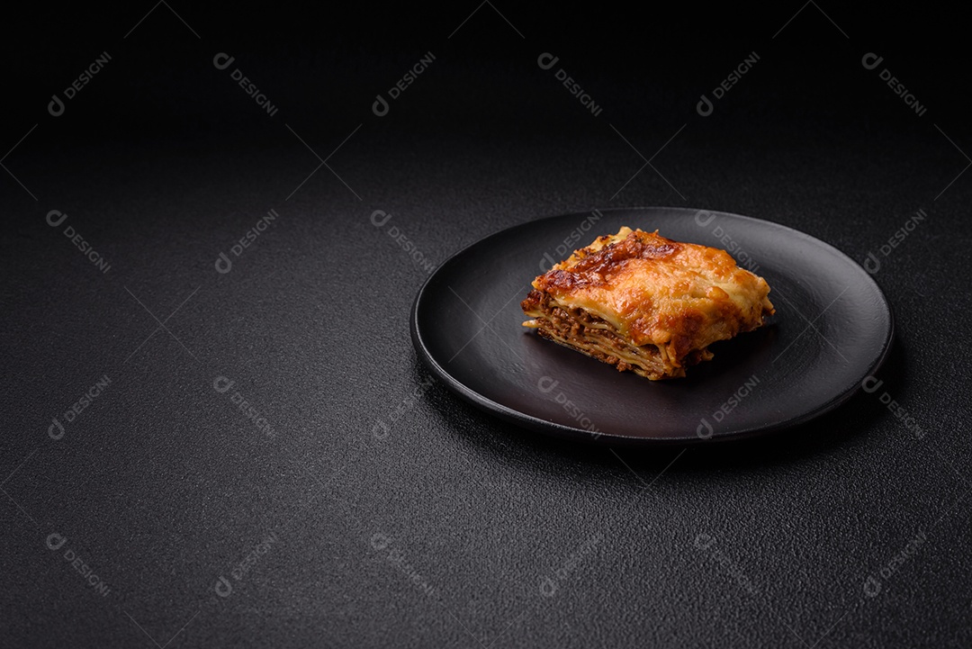 Deliciosa massa de lasanha assada com carne, molho, sal, especiarias e ervas sobre um fundo escuro de concreto
