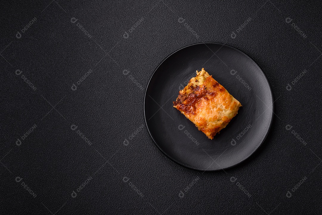 Deliciosa massa de lasanha assada com carne, molho, sal, especiarias e ervas sobre um fundo escuro de concreto