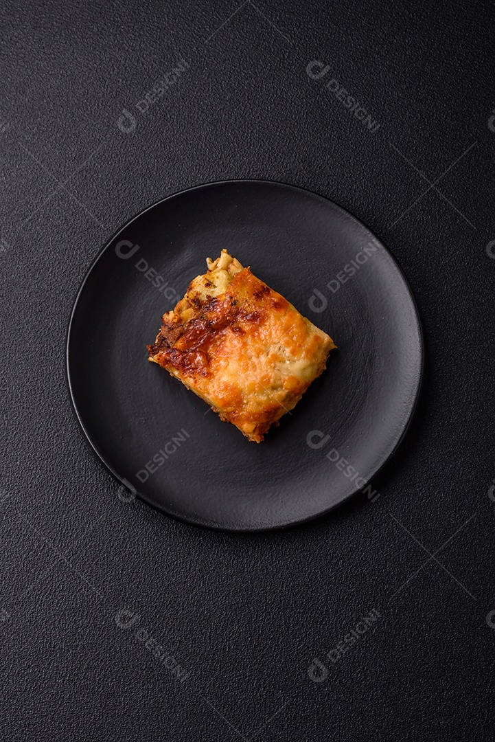 Deliciosa massa de lasanha assada com carne, molho, sal, especiarias e ervas sobre um fundo escuro de concreto