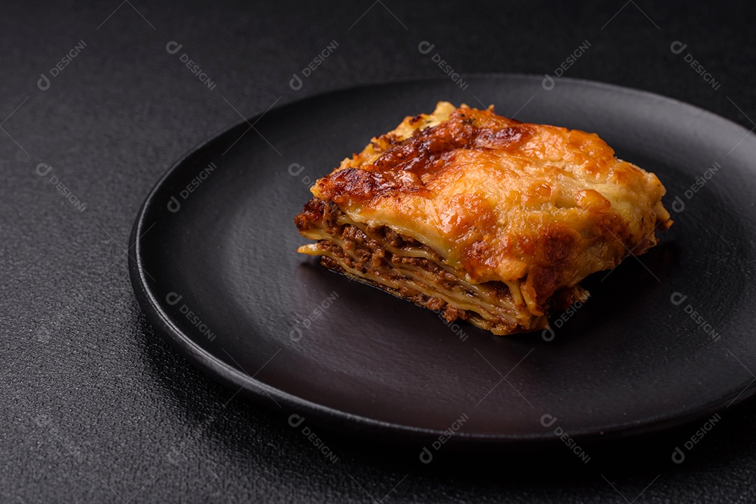 Deliciosa massa de lasanha assada com carne, molho, sal, especiarias e ervas sobre um fundo escuro de concreto