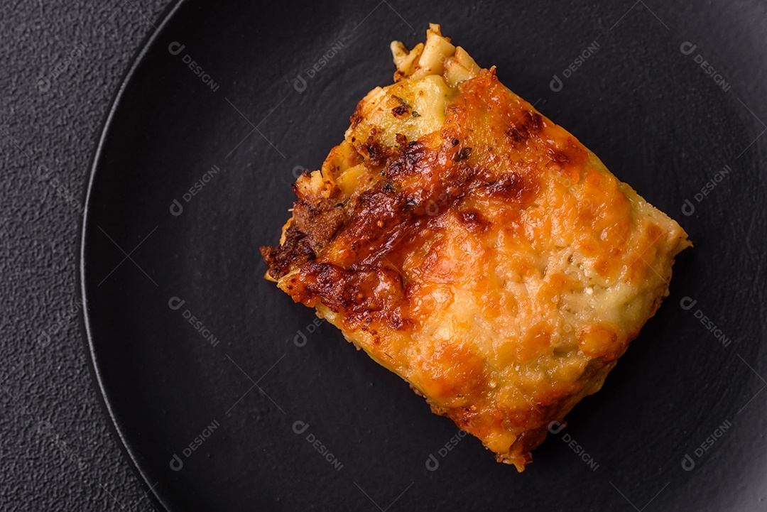 Deliciosa massa de lasanha assada com carne, molho, sal, especiarias e ervas sobre um fundo escuro de concreto