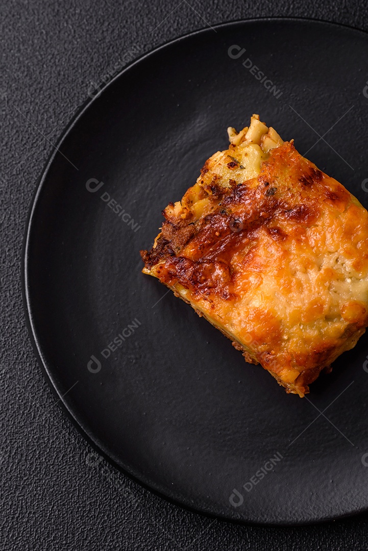 Deliciosa massa de lasanha assada com carne, molho, sal, especiarias e ervas sobre um fundo escuro de concreto