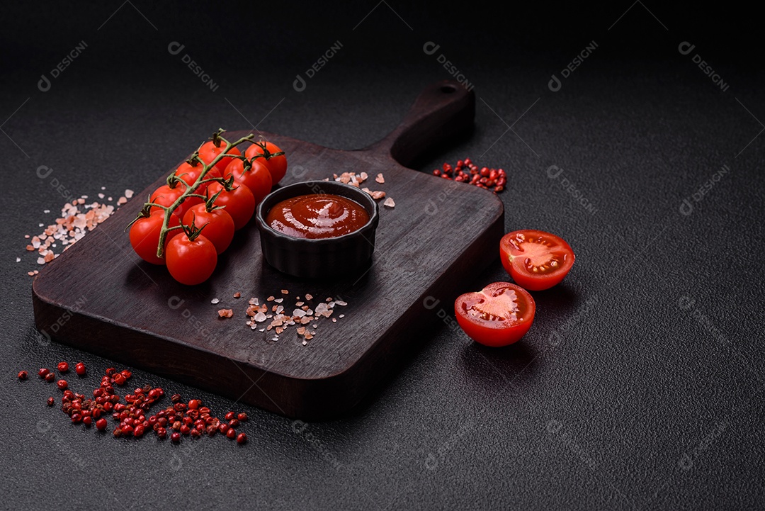 Delicioso molho de tomate picante com pimenta, alho, sal, especiarias e ervas em uma molheira branca sobre um fundo escuro de concreto