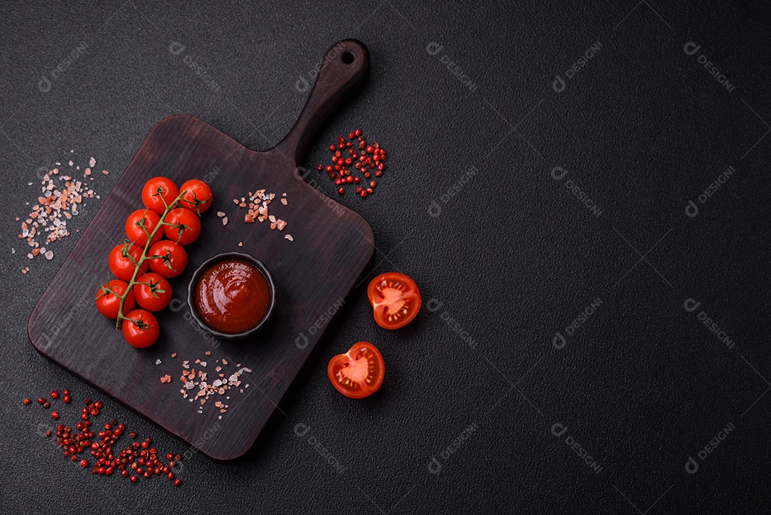 Delicioso molho de tomate picante com pimenta, alho, sal, especiarias e ervas em uma molheira branca sobre um fundo escuro de concreto