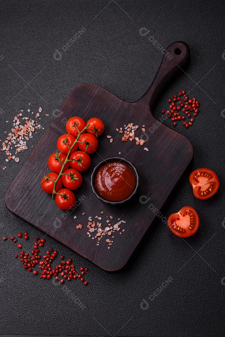 Delicioso molho de tomate picante com pimenta, alho, sal, especiarias e ervas em uma molheira branca sobre um fundo escuro de concreto