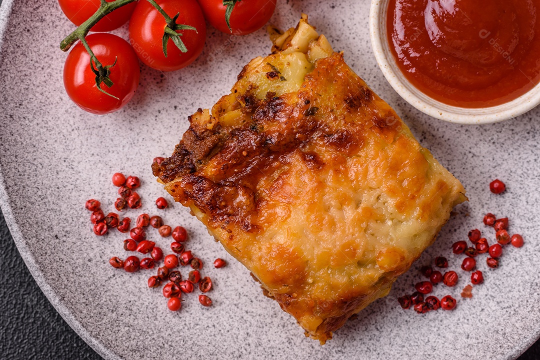 Deliciosa massa de lasanha assada com carne, molho, sal, especiarias e ervas sobre um fundo escuro de concreto