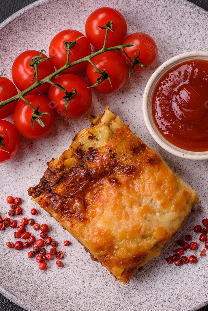 Deliciosa massa de lasanha assada com carne, molho, sal, especiarias e ervas sobre um fundo escuro de concreto