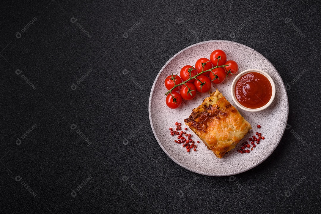 Deliciosa massa de lasanha assada com carne, molho, sal, especiarias e ervas sobre um fundo escuro de concreto