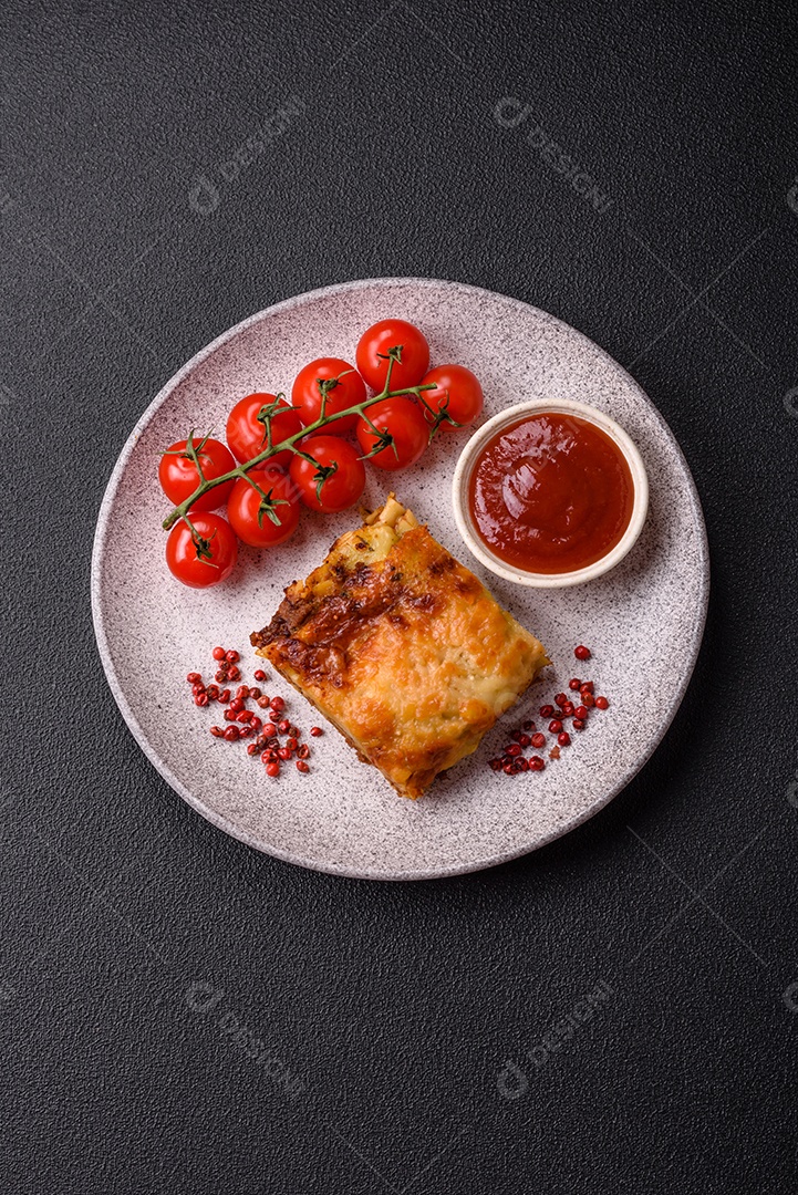 Deliciosa massa de lasanha assada com carne, molho, sal, especiarias e ervas sobre um fundo escuro de concret