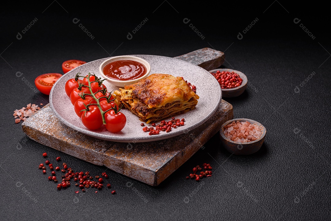 Deliciosa massa de lasanha assada com carne, molho, sal, especiarias e ervas sobre um fundo escuro de concreto