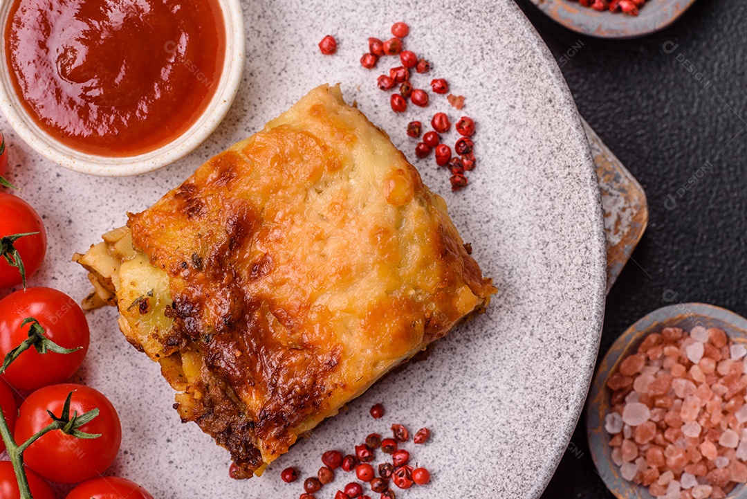 Deliciosa massa de lasanha assada com carne, molho, sal, especiarias e ervas sobre um fundo escuro de concreto