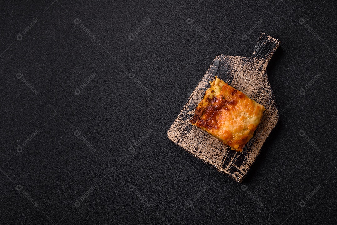 Deliciosa massa de lasanha assada com carne, molho, sal, especiarias e ervas sobre um fundo escuro de concreto