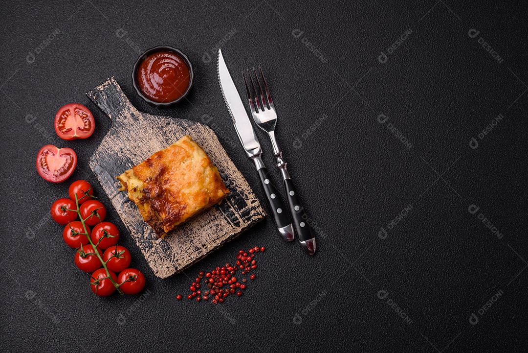Deliciosa massa de lasanha assada com carne, molho, sal, especiarias e ervas sobre um fundo escuro de concreto
