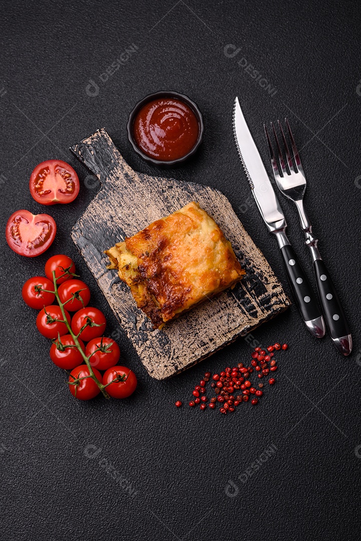 Deliciosa massa de lasanha assada com carne, molho, sal, especiarias e ervas sobre um fundo escuro de concreto