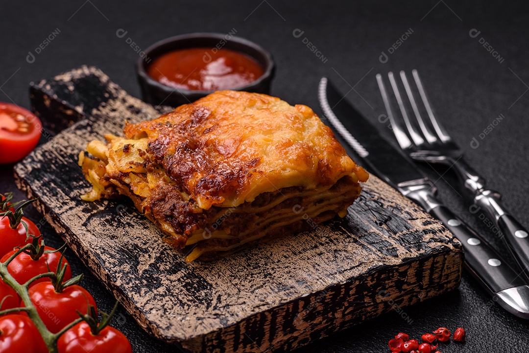 Deliciosa massa de lasanha assada com carne, molho, sal, especiarias e ervas sobre um fundo escuro de concreto