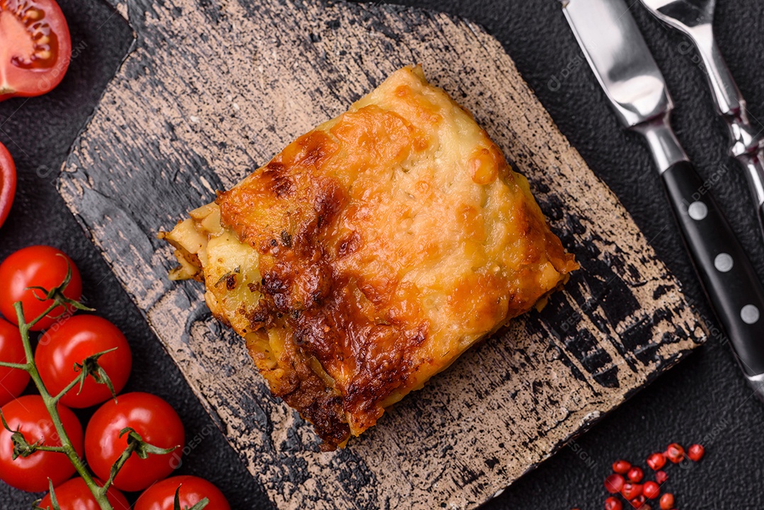 Deliciosa massa de lasanha assada com carne, molho, sal, especiarias e ervas sobre um fundo escuro de concreto