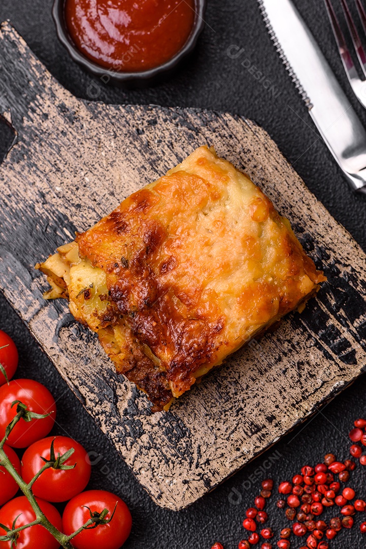 Deliciosa massa de lasanha assada com carne, molho, sal, especiarias e ervas sobre um fundo escuro de concreto
