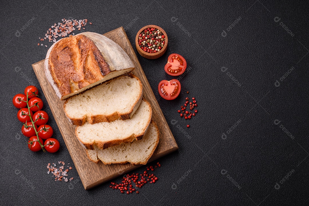 Um pedaço de pão integral com grãos de cereais em uma tábua de madeira sobre um fundo escuro de concreto