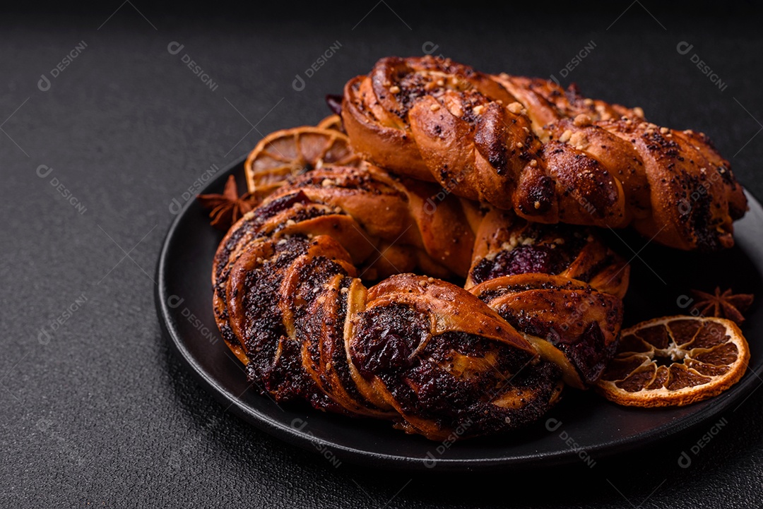 Delicioso pão fresco com sementes de papoila e bagas em forma de anel sobre um fundo escuro de concreto