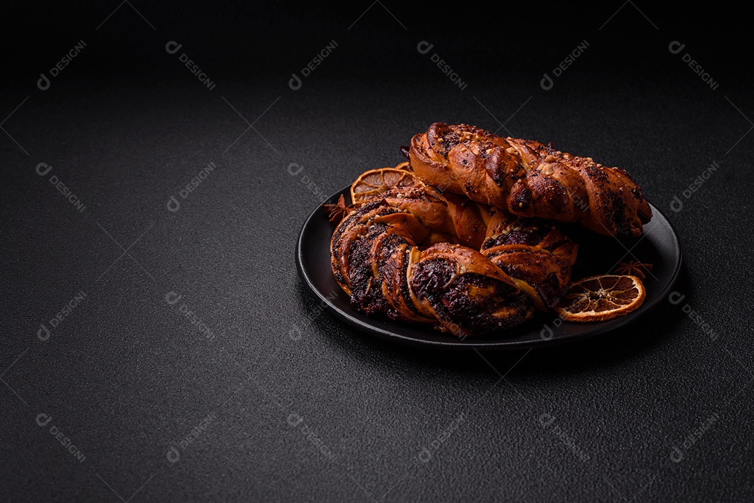 Delicioso pão fresco com sementes de papoila e bagas em forma de anel sobre um fundo escuro de concreto