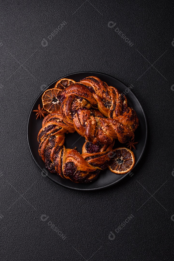 Delicioso pão fresco com sementes de papoila e bagas em forma de anel sobre um fundo escuro de concreto