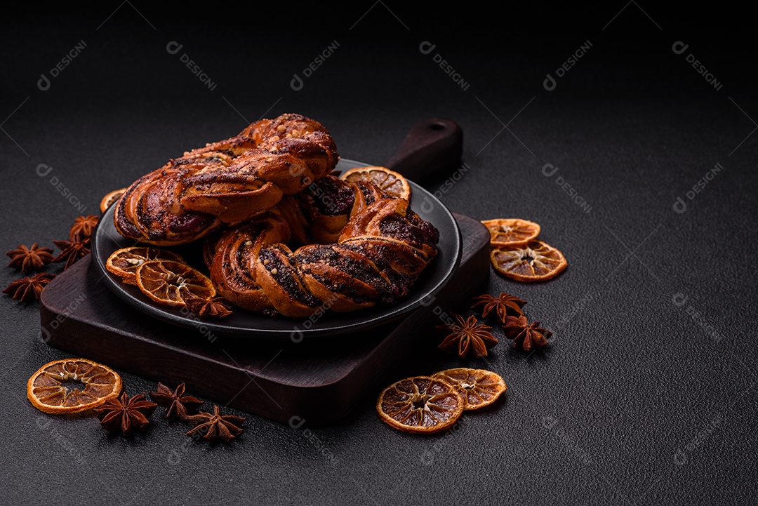 Delicioso pão fresco com sementes de papoila e bagas em forma de anel sobre um fundo escuro de concreto